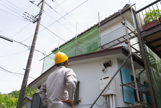 リフォーム中の家を見上げる業者